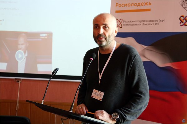 Участник с трибунным микрофоном на семинаре российско-германских обменов